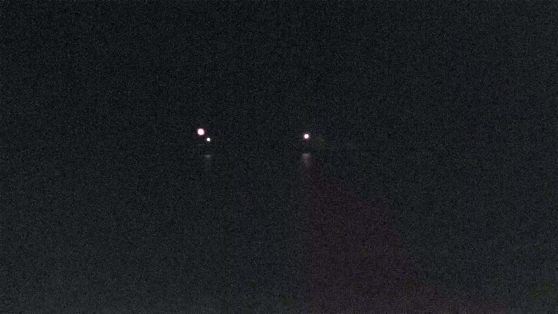 Two faint red lights are visible in the inky blackness of night.