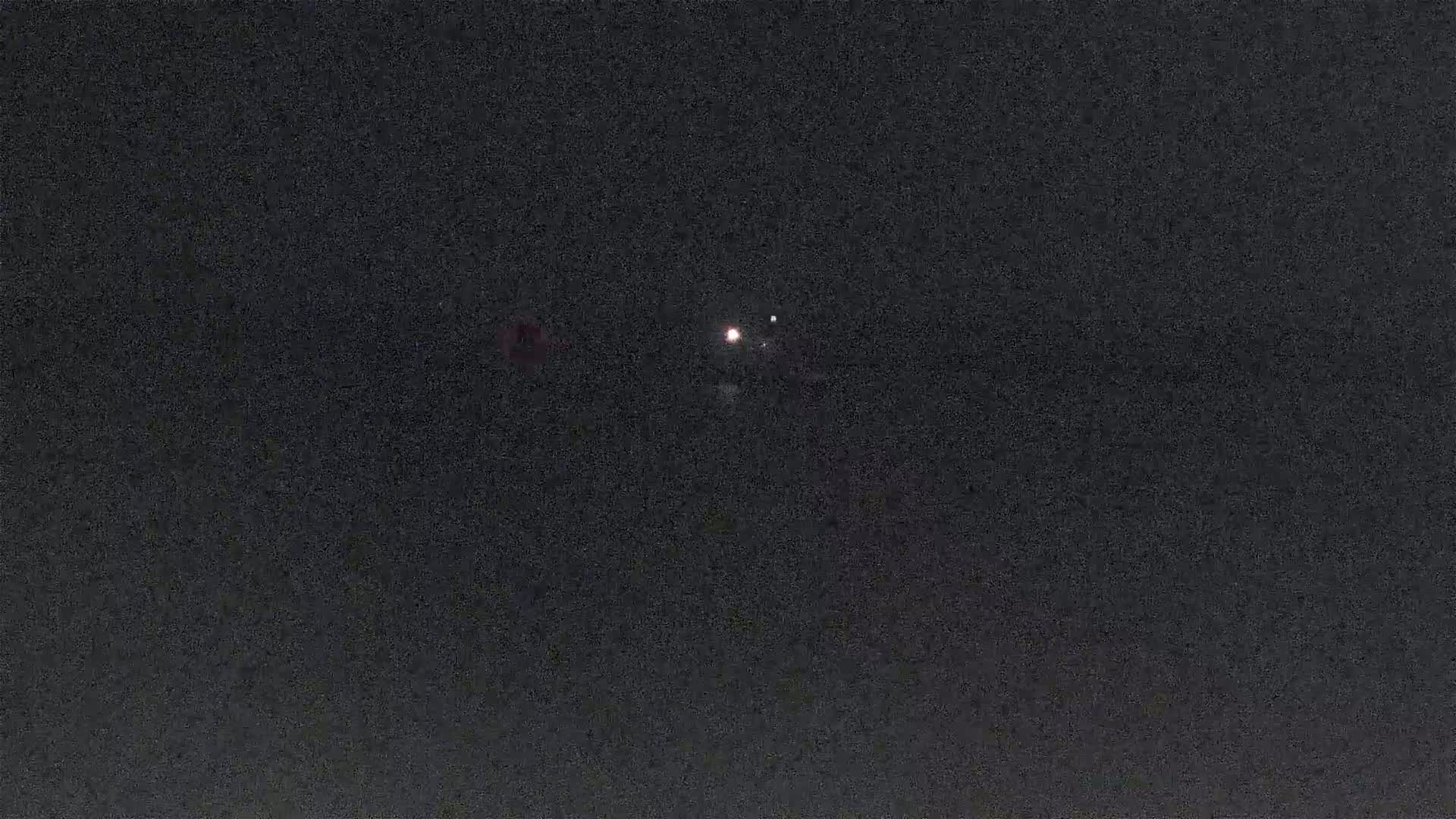 A nighttime image shows three bright lights in a dark sky.