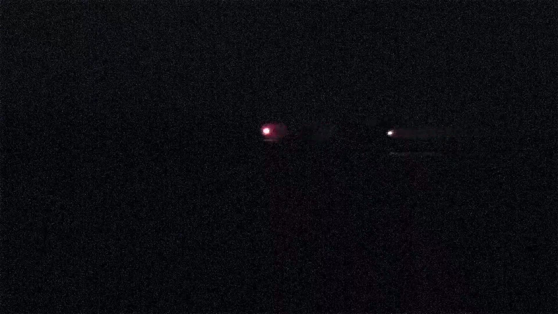 A dark night scene shows two small lights in the distance.
