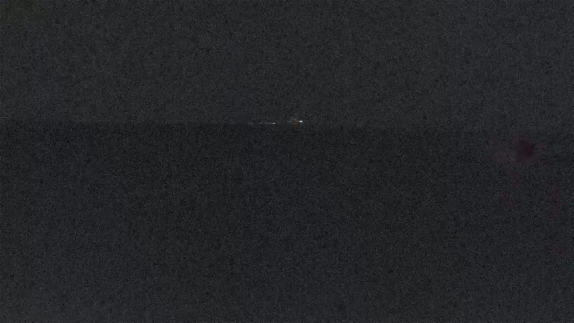 A faintly lit object is visible on a dark, nighttime horizon.