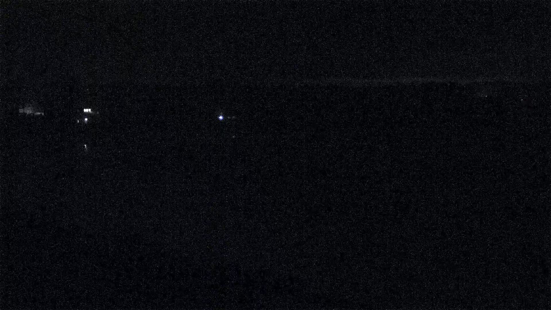 A nighttime view shows a dark landscape with a few distant, faint lights.
