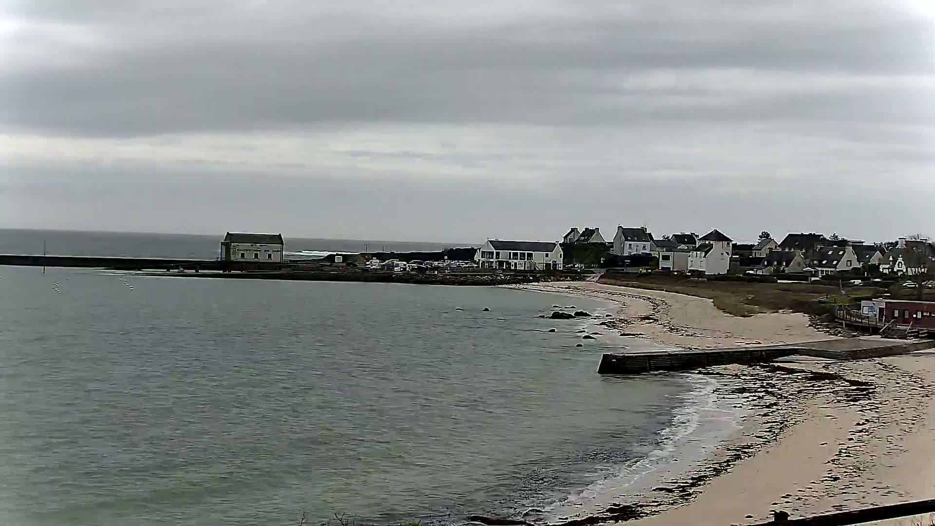 A coastal town with a sandy beach is visible under an overcast sky.