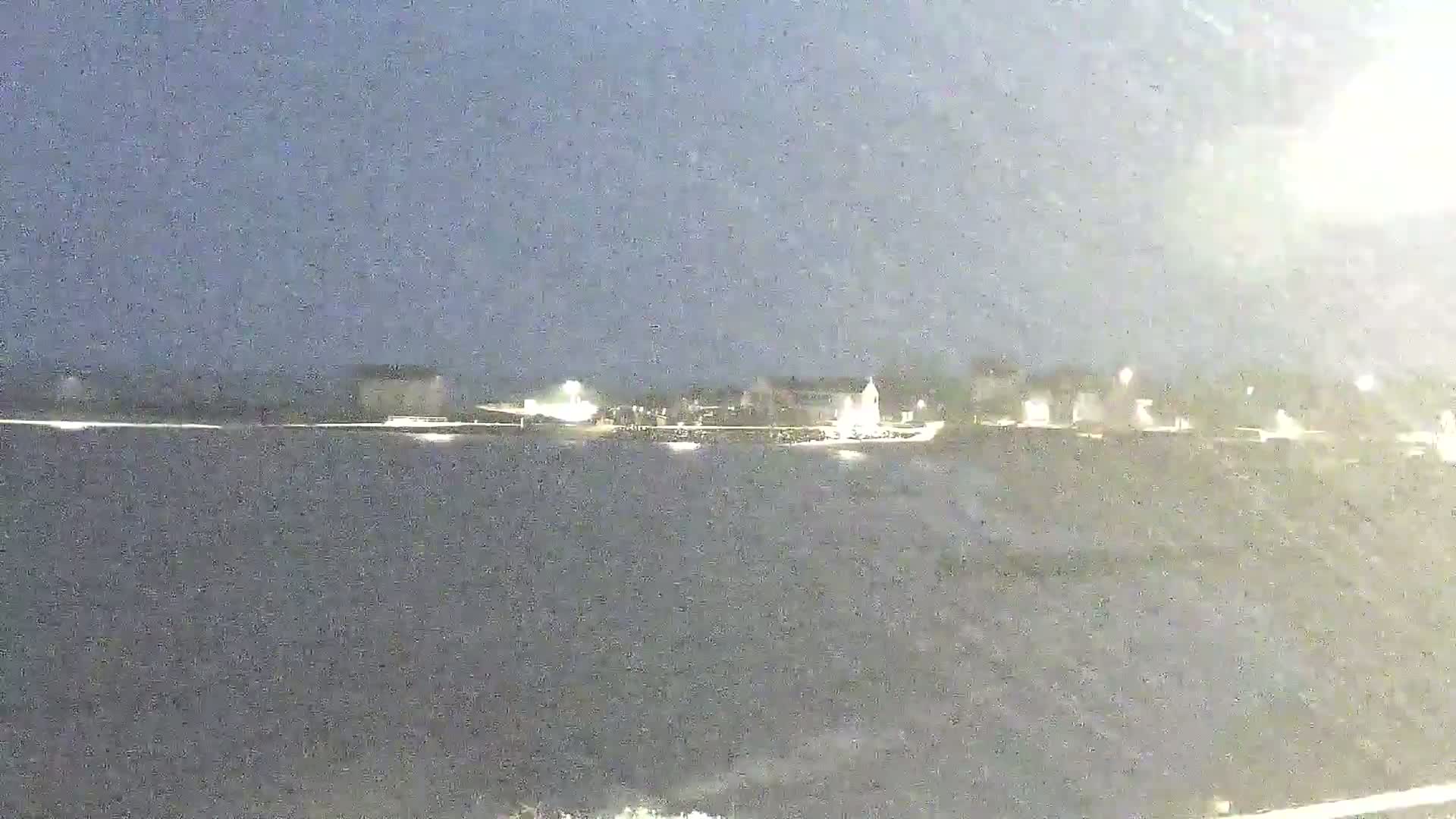 A dimly lit shoreline with buildings and a body of water under an overcast sky.