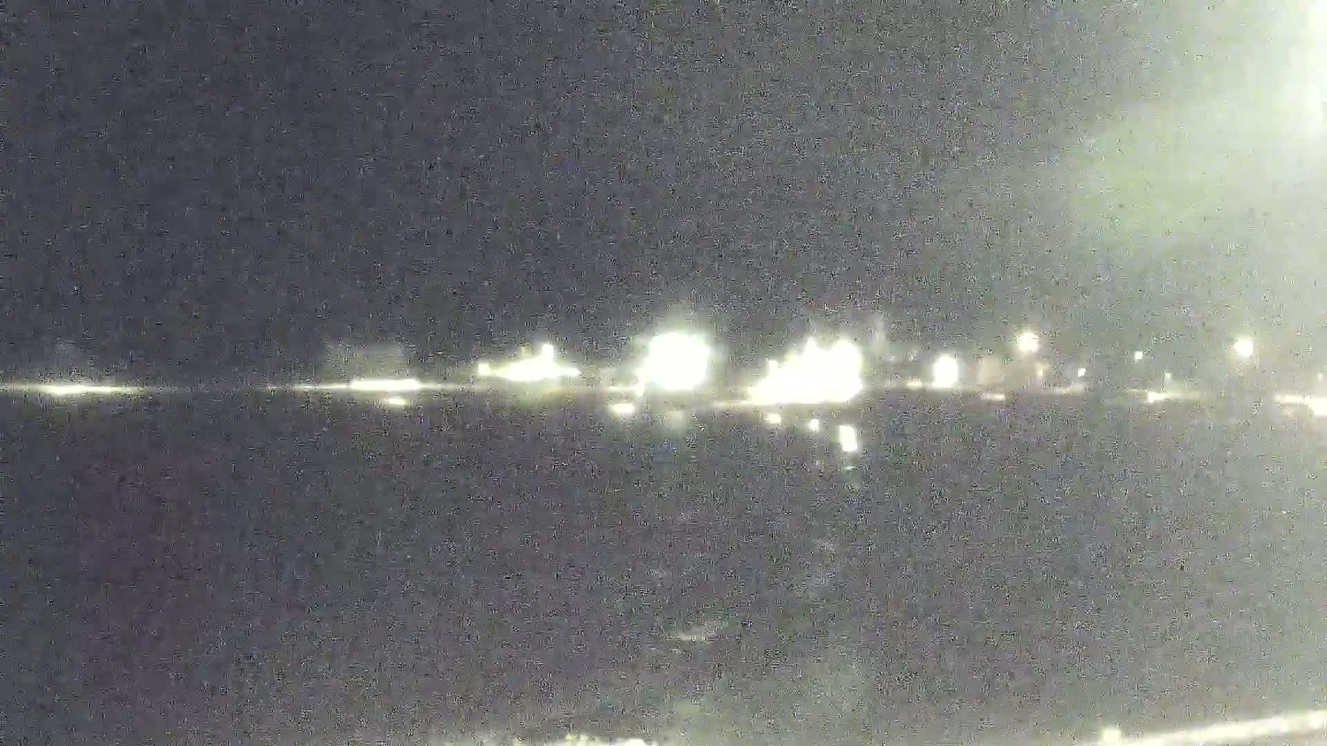 At night, distant lights illuminate a dark body of water reflecting a faint glow.