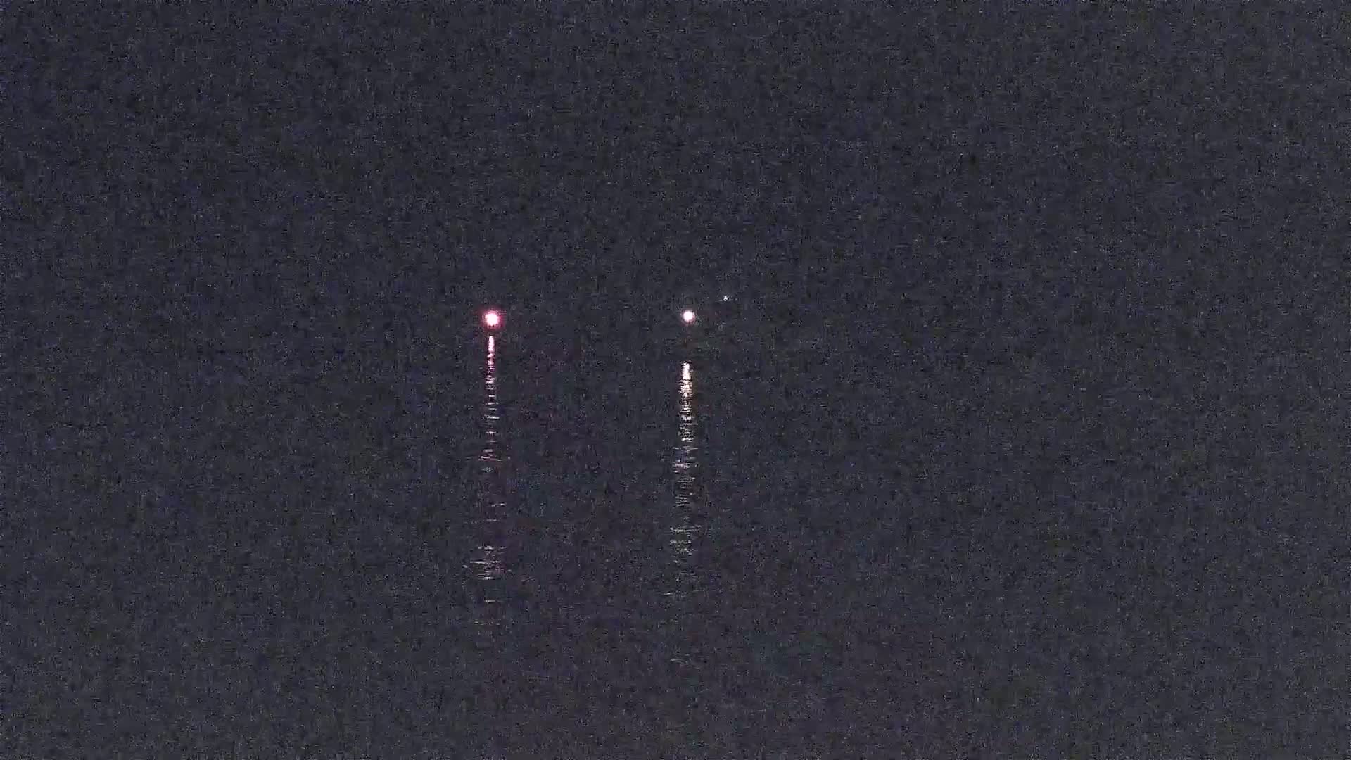 Three lights are visible on the dark water at night.
