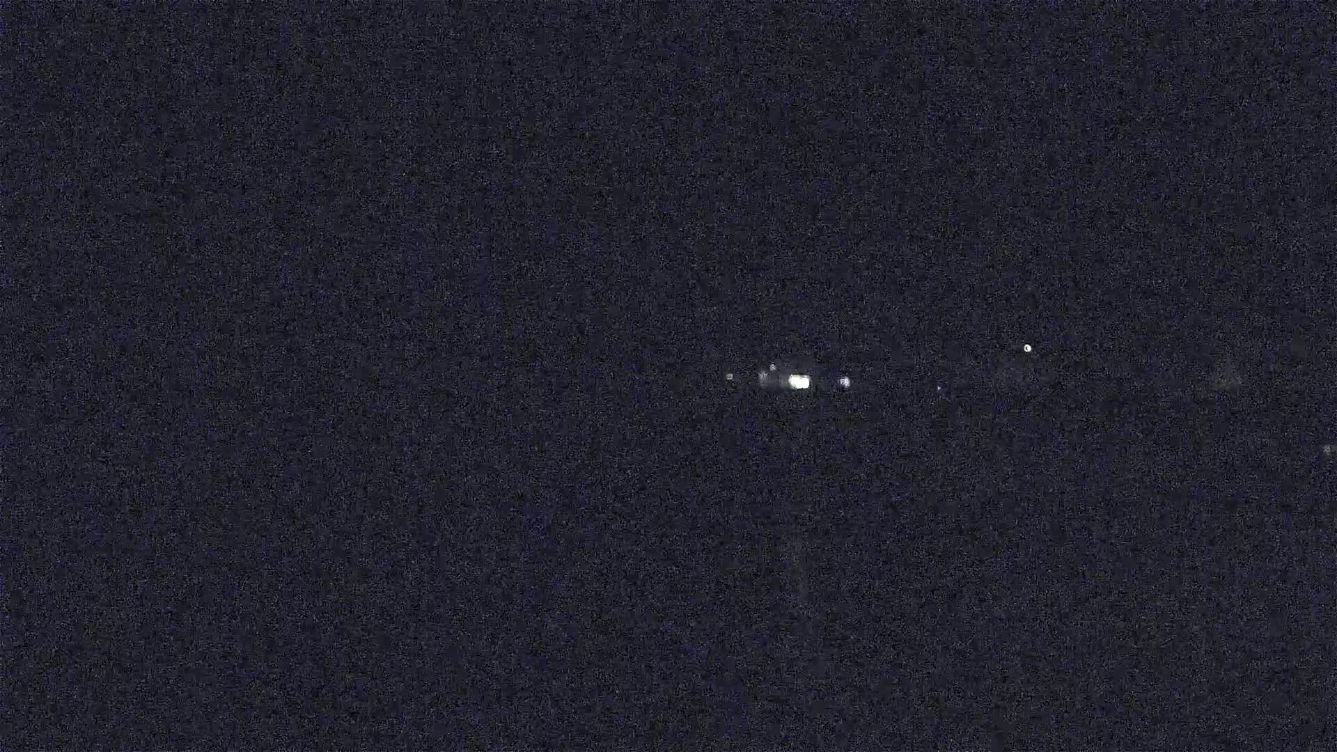 A nighttime image shows a cluster of faint lights in the distance.