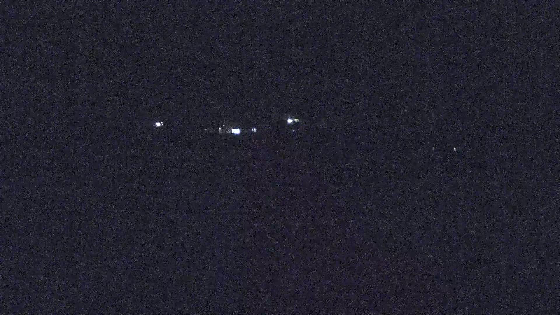 At night, a few distant lights are visible in the dark.