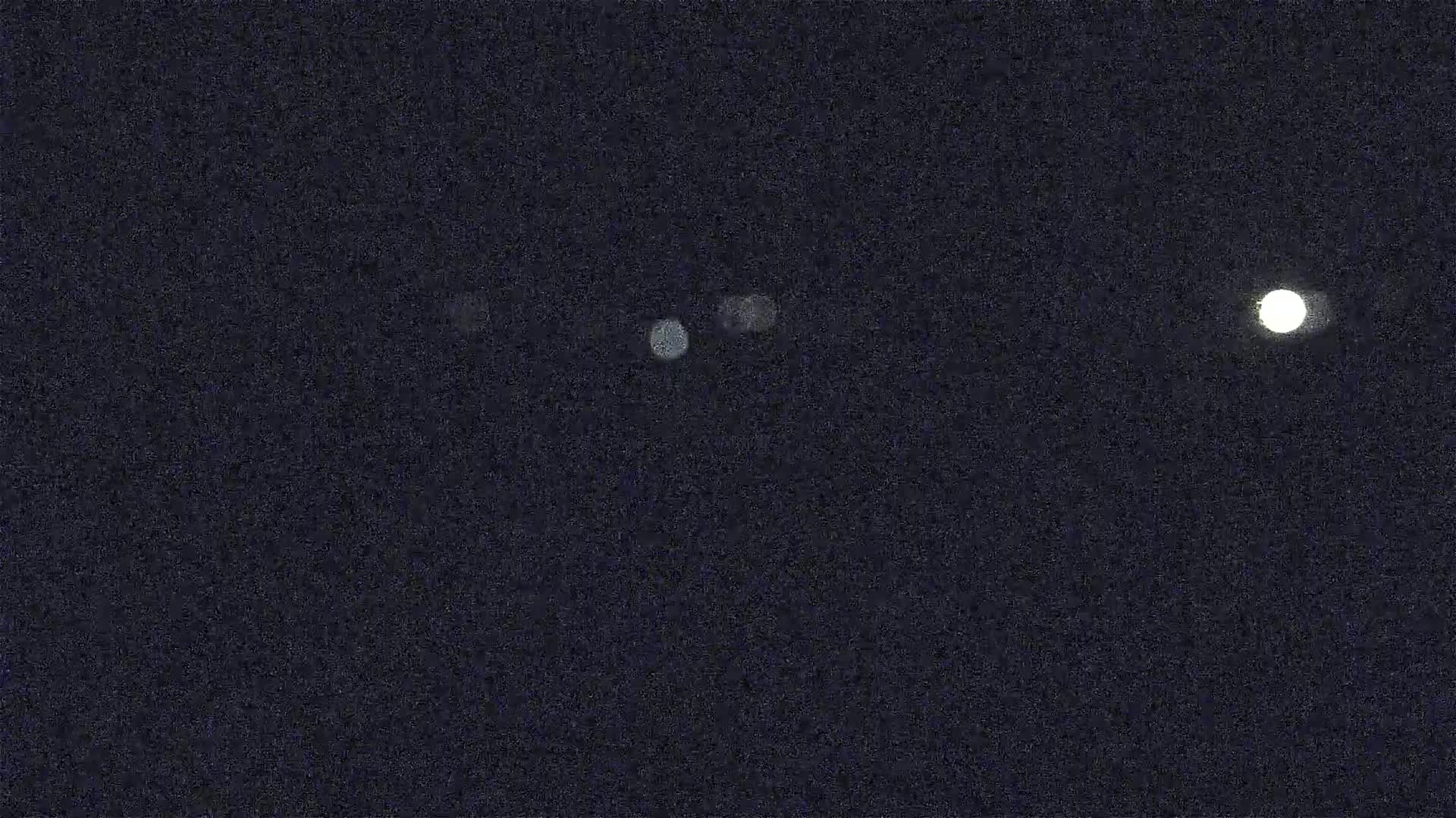 A bright moon and several fainter lights are visible in a dark night sky.