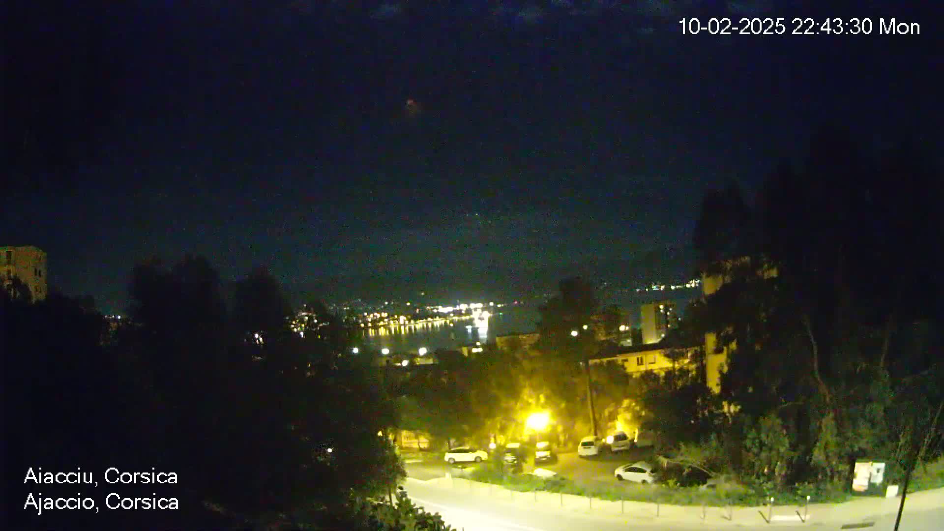 A nighttime view of a city overlooking a body of water under a clear, dark sky.