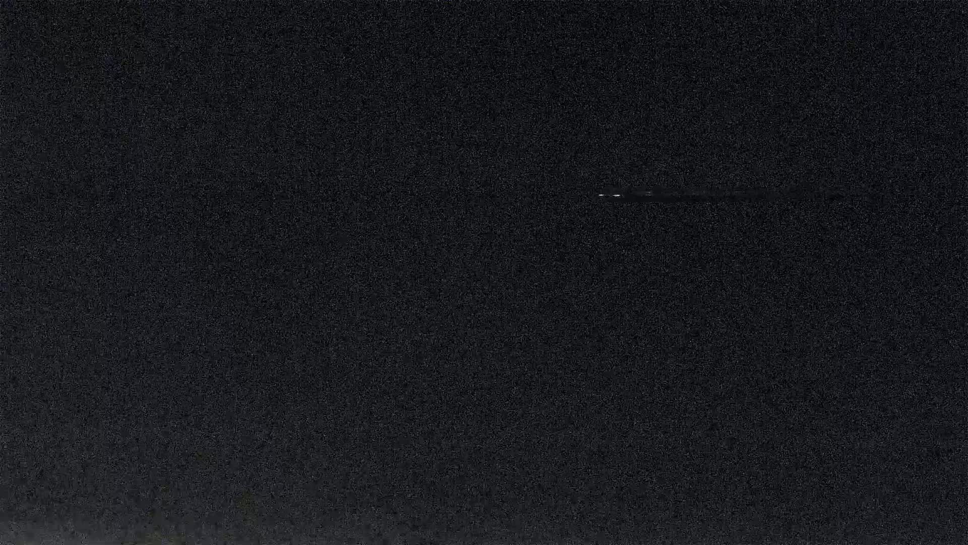 A dark, nighttime image shows a faint, thin line of light across a mostly black sky.