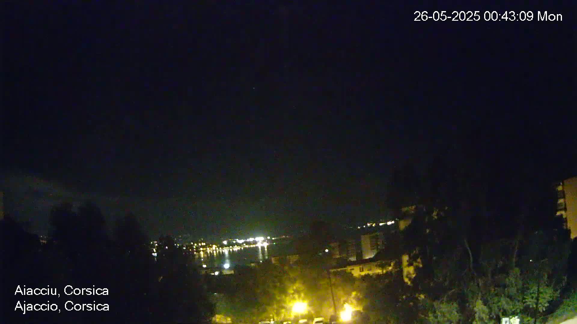 A nighttime view of a city and body of water, under a clear, dark sky.