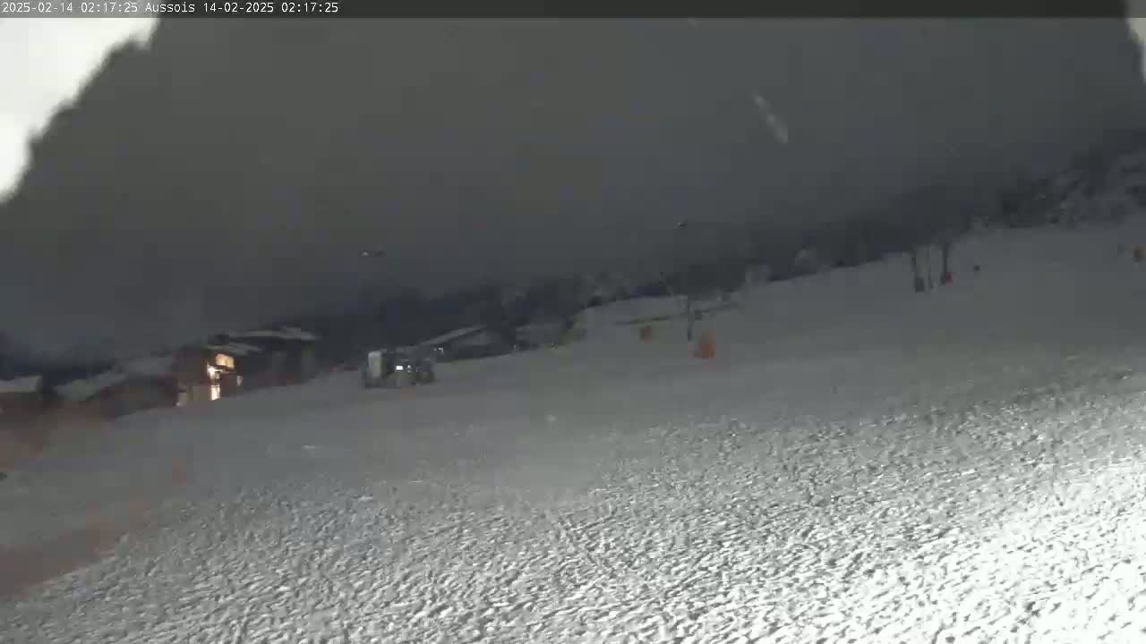 A snow-covered slope at night under a dark, cloudy sky.