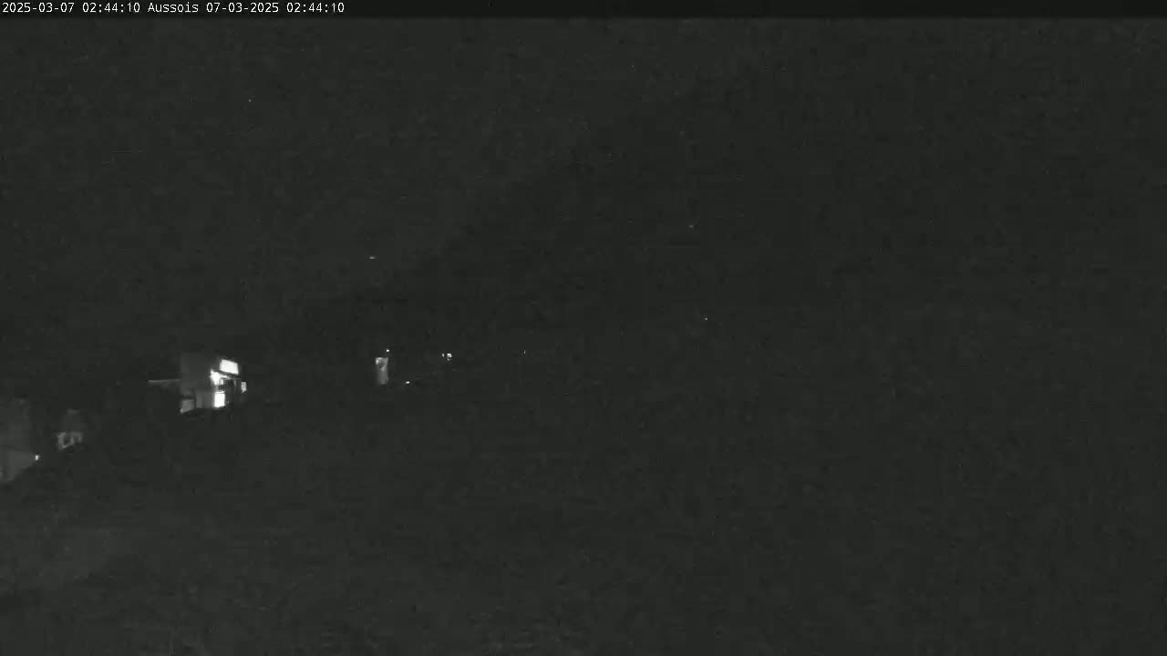 A dimly lit nighttime scene shows a few faint lights in the distance.