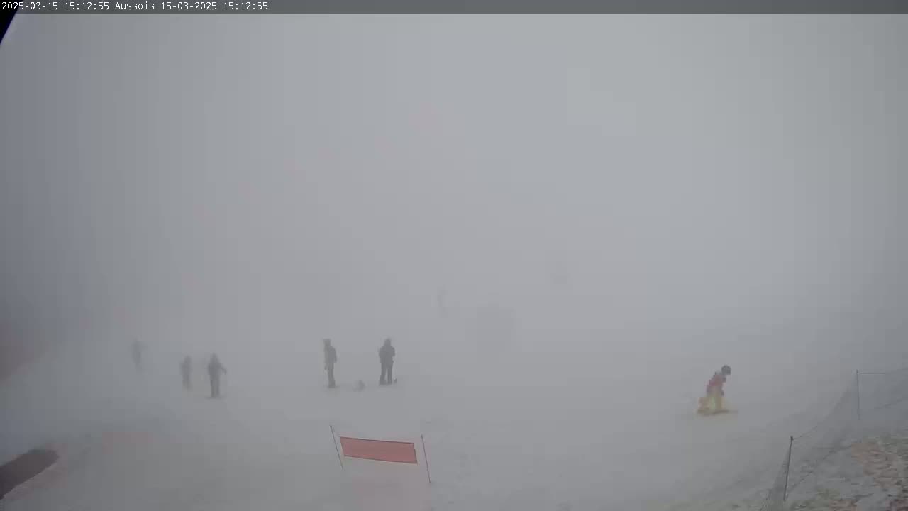 A thick fog obscures several figures on a snowy, flat expanse.