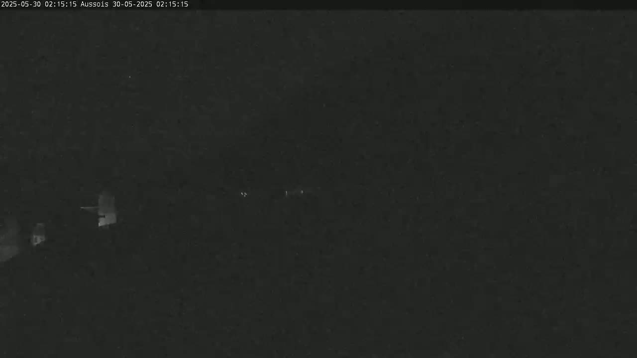 A nighttime, low-light image shows indistinct shapes that may be buildings in the distance under a dark sky.