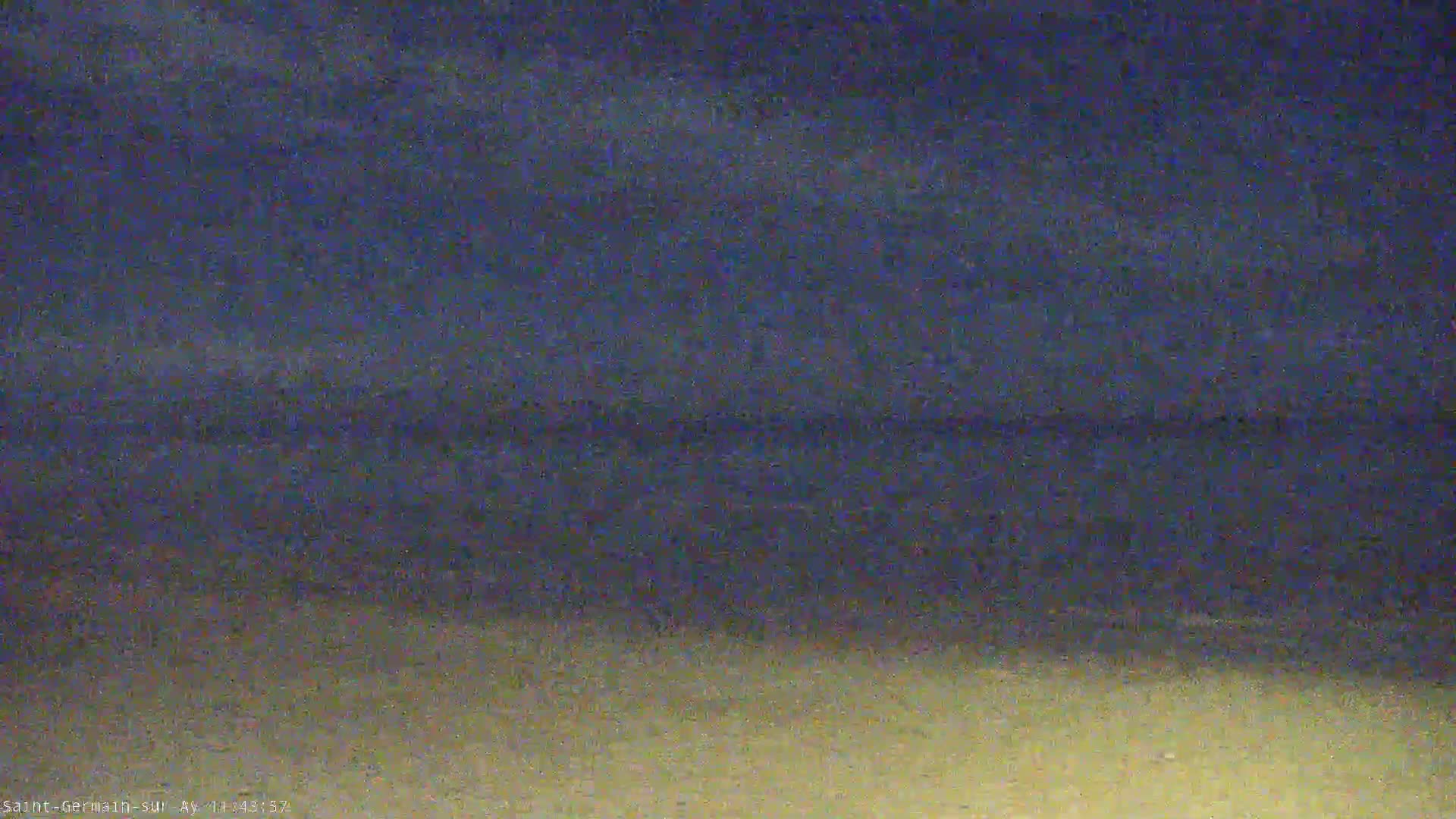 A dark beach at night is shown under a mostly clear, dark blue sky.