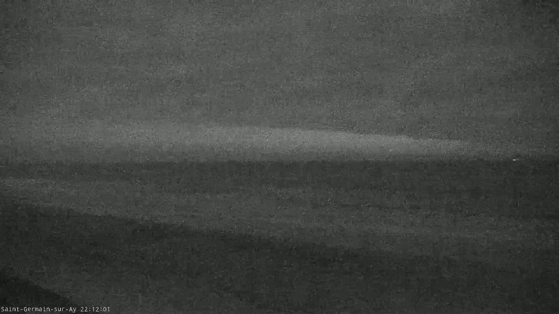 A low-light, grainy image shows a dark, possibly nighttime, landscape with a faint horizon line.