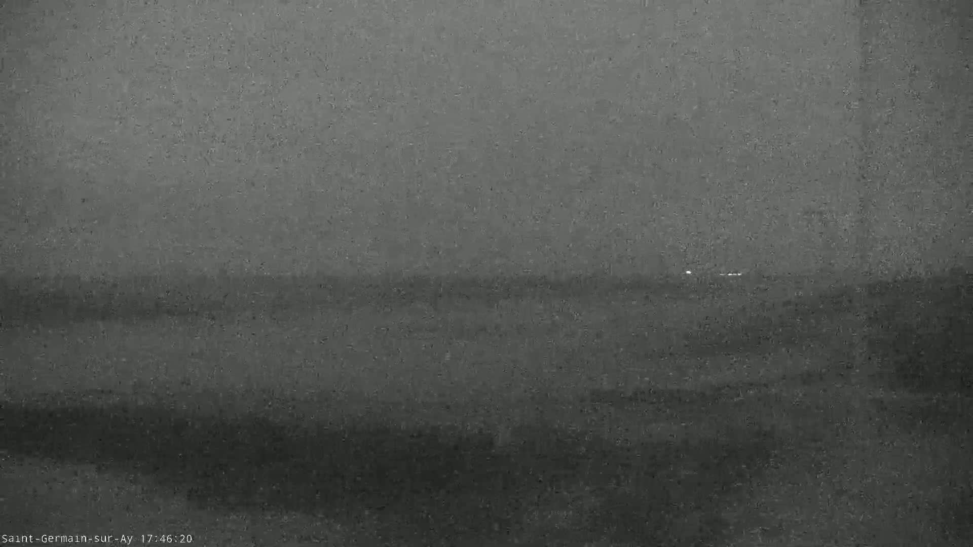 A dark, overcast sky hangs over a calm, gray body of water.