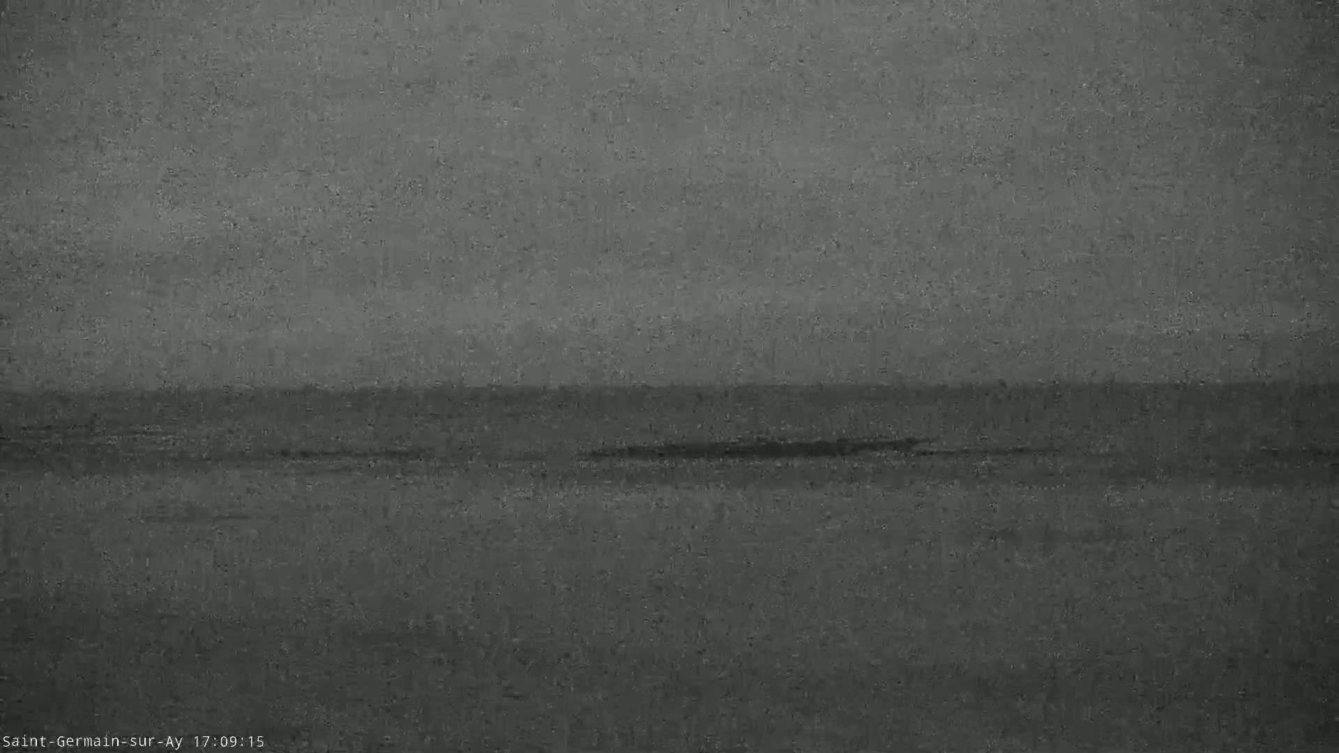 A dark, overcast sky hangs over a calm, gray body of water.