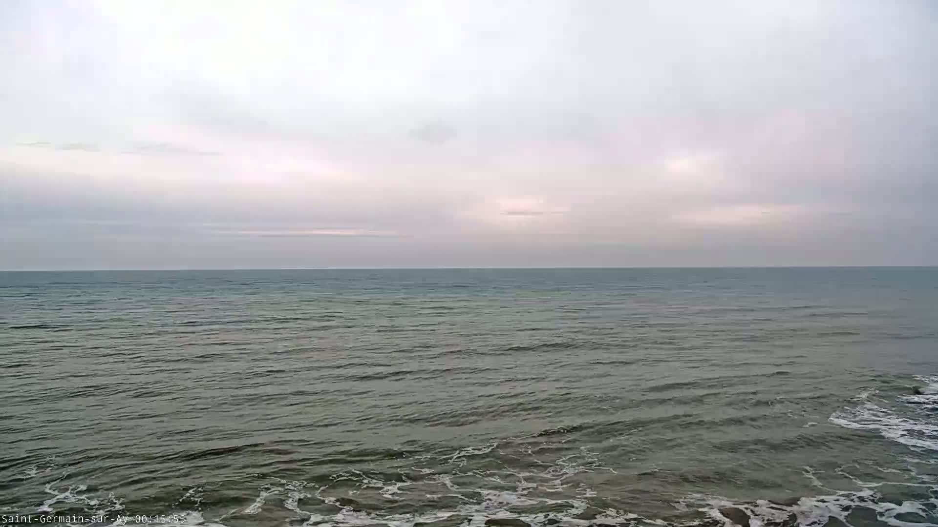 A calm, grey sea stretches to a pale, overcast sky.