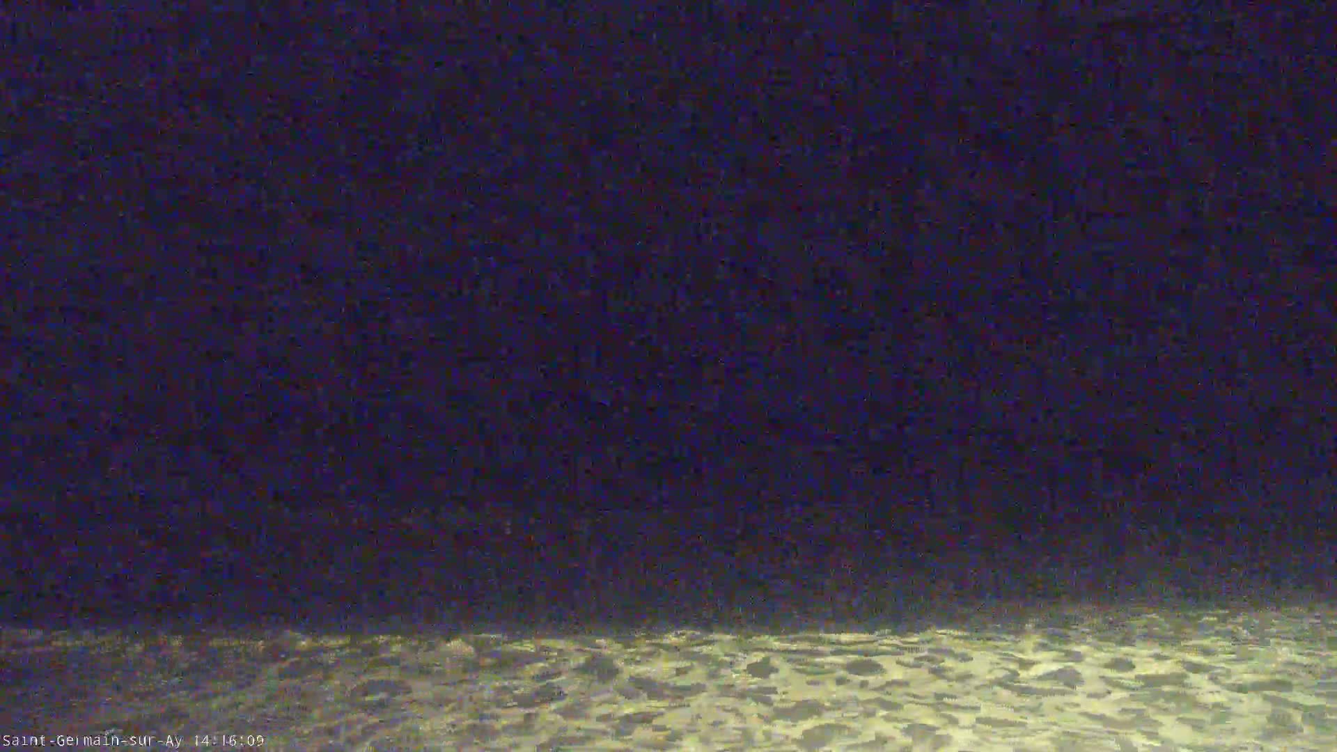 A nighttime, low-light view shows a dark sky over a lightly textured, possibly watery, surface.