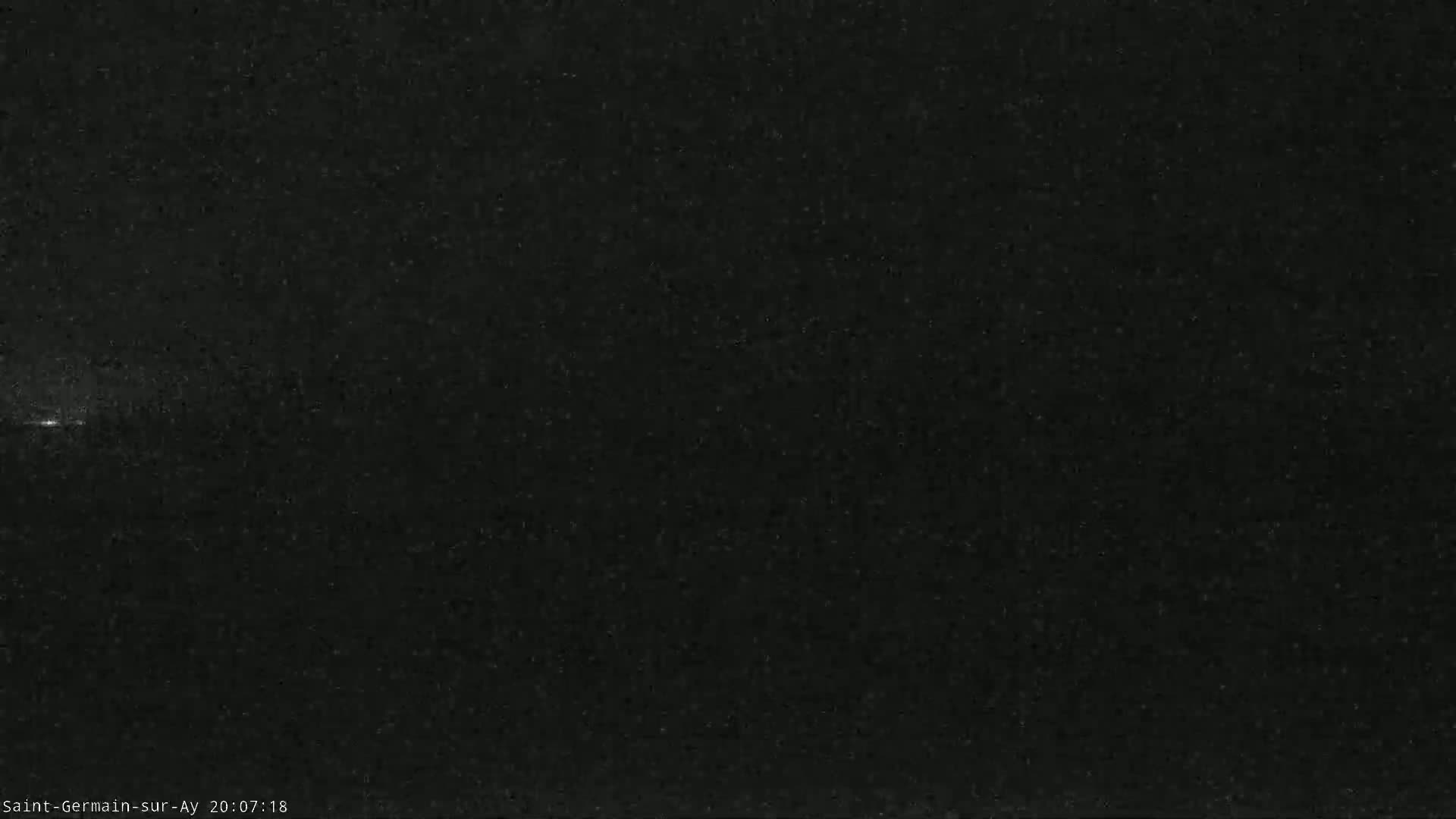 A dark, mostly black, nighttime outdoor scene shows a faint, horizontal streak of light across the image.