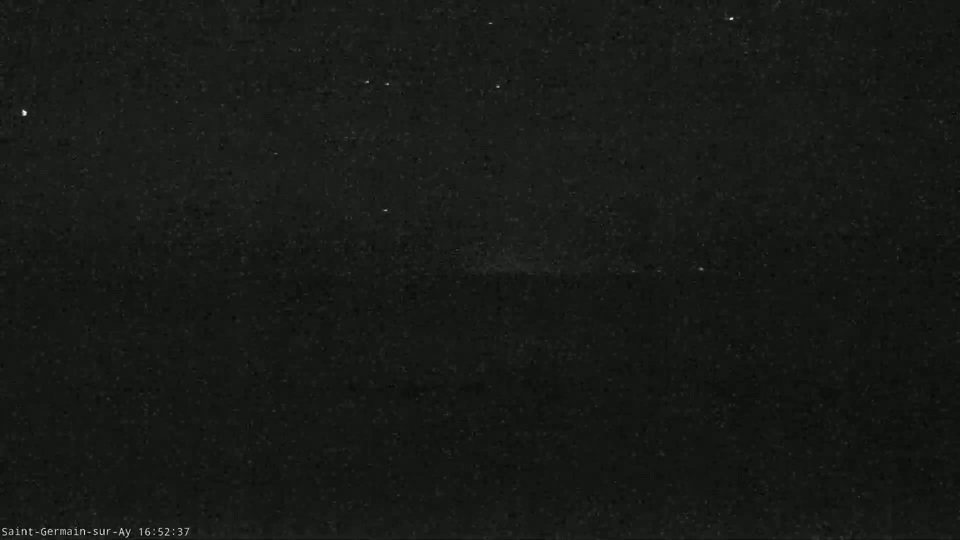 A dark, grainy image shows a night sky with a faint, blurry horizon line.