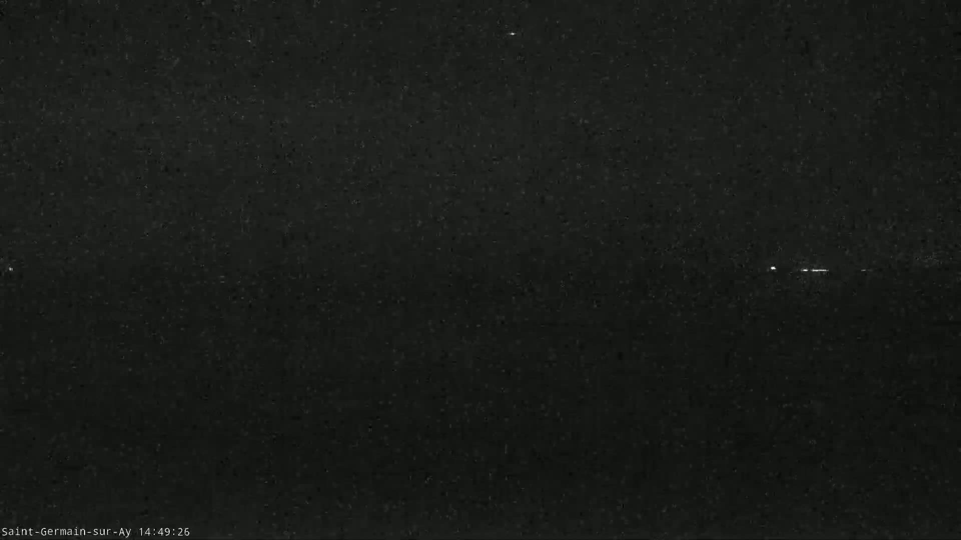 A nighttime image shows a dark, possibly cloudy, sky with a few faint lights visible in the distance.