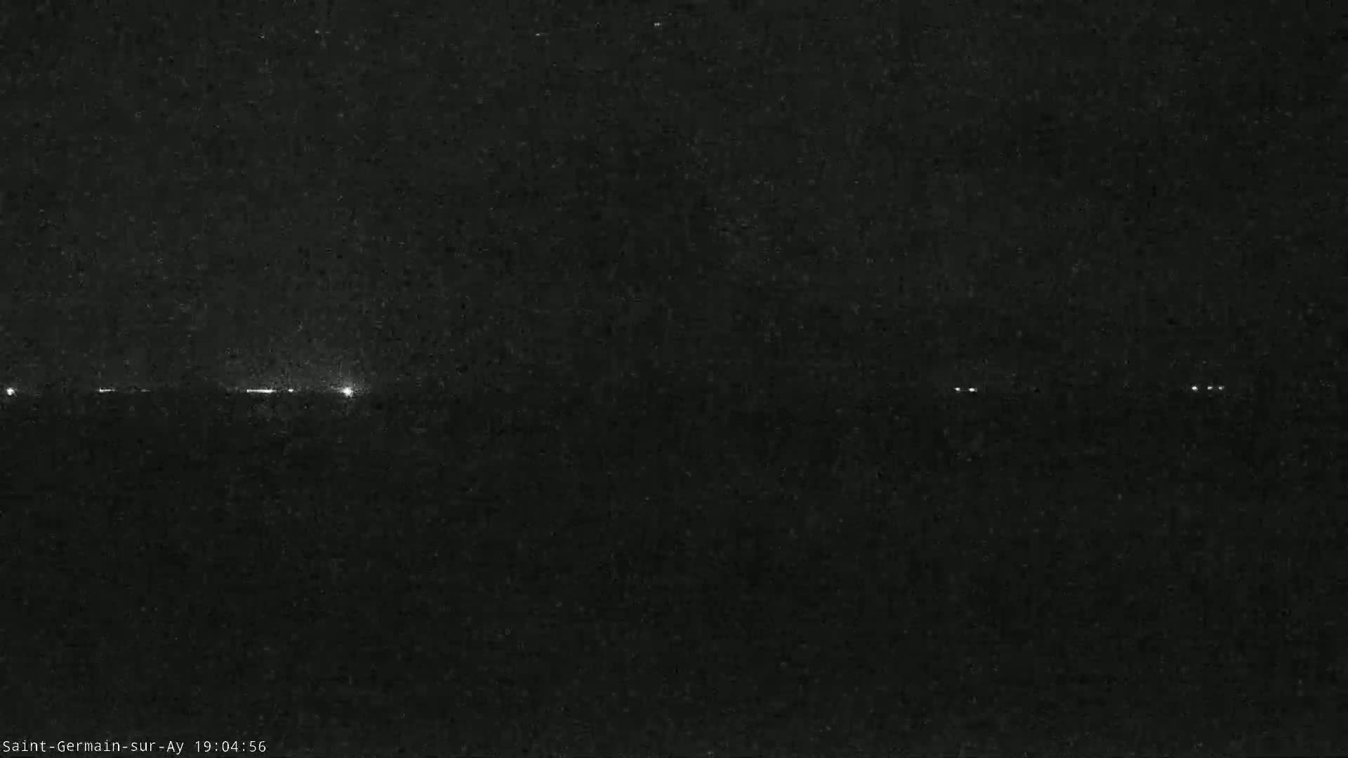 A dark, nighttime scene shows a faint, horizontal line of lights in the distance under a clear sky.