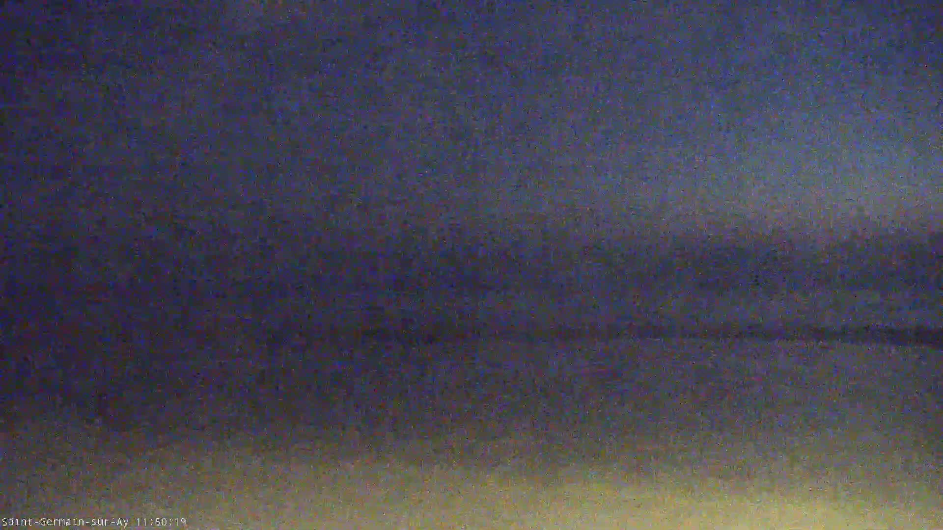 A blurry, dark image shows a dusky, possibly twilight sky over a flat, indistinct landscape.