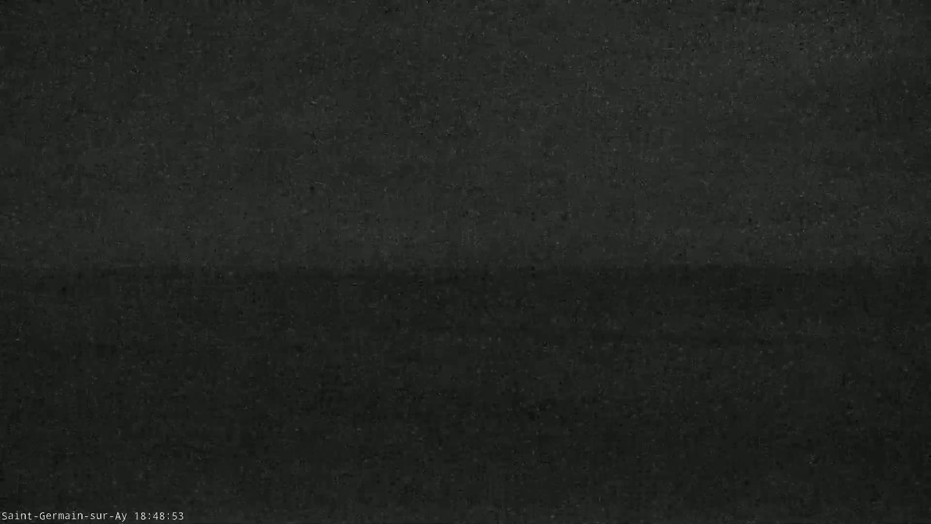 A dark, blurry image shows a mostly featureless expanse of land under a dark sky.