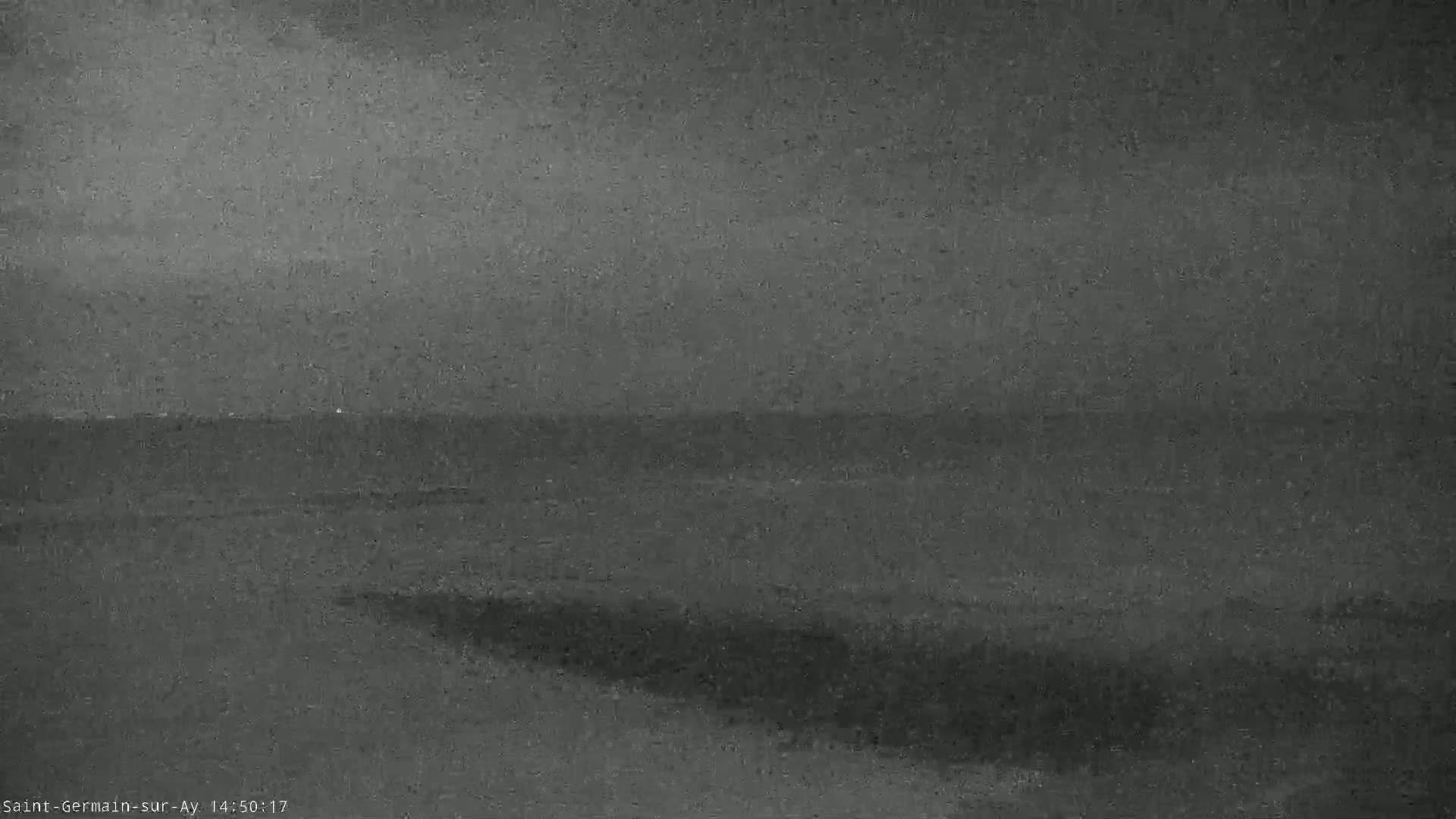 A low-quality, dark gray image shows a body of water under an overcast sky.