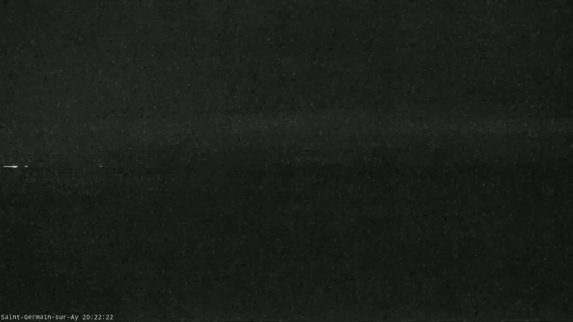 A dark, grainy nighttime image shows a faint, horizontal line of light in the distance.