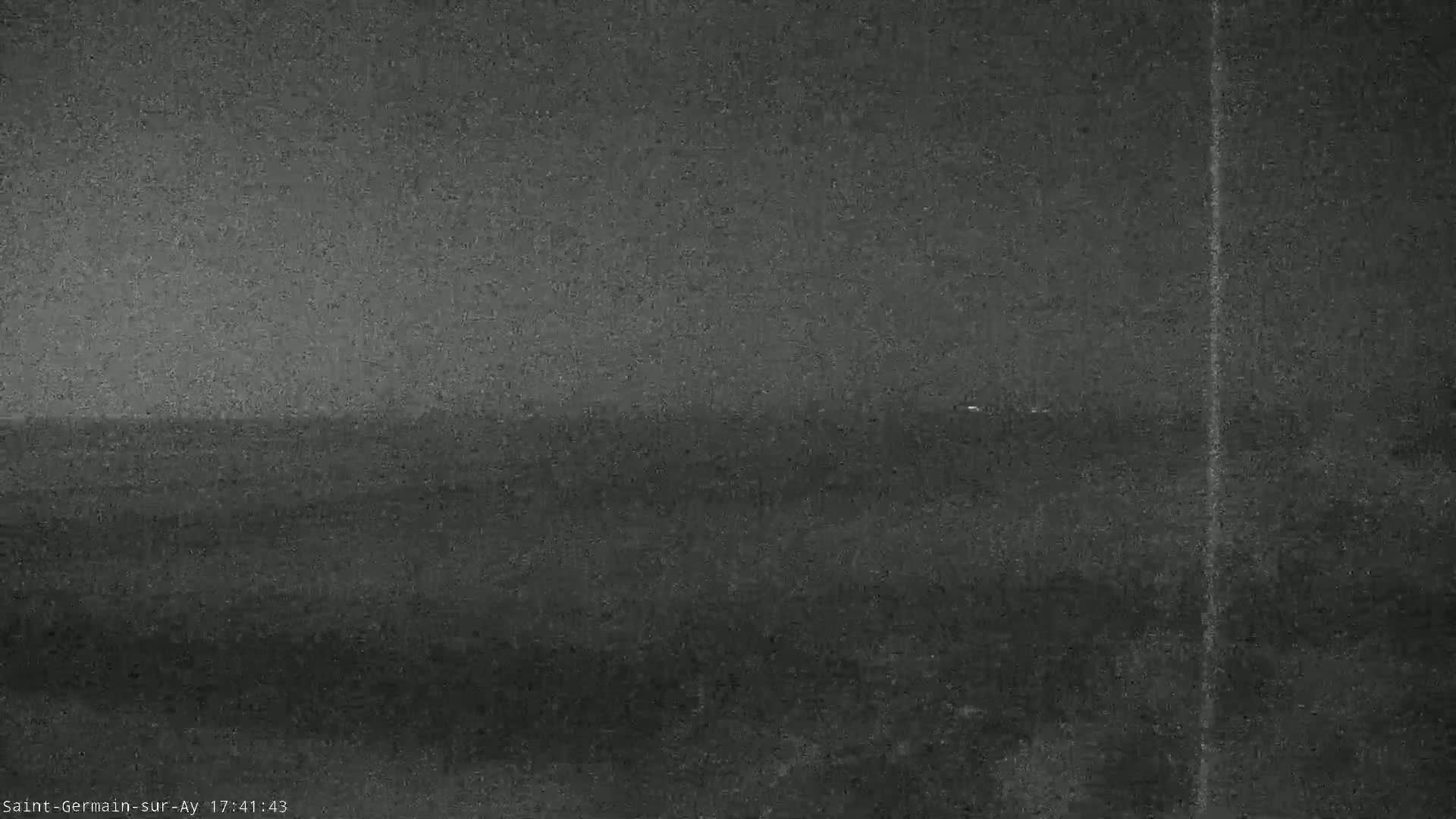 A low-light, grainy image shows a dark, flat landscape under an overcast sky.