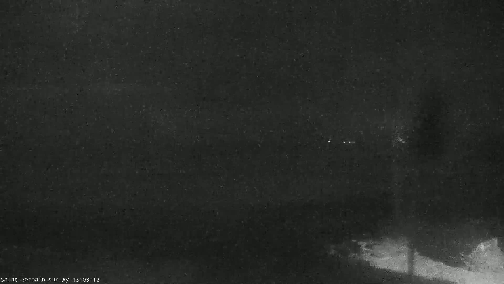 A dark, nighttime scene with some faint lights in the distance and possibly snow on the ground.