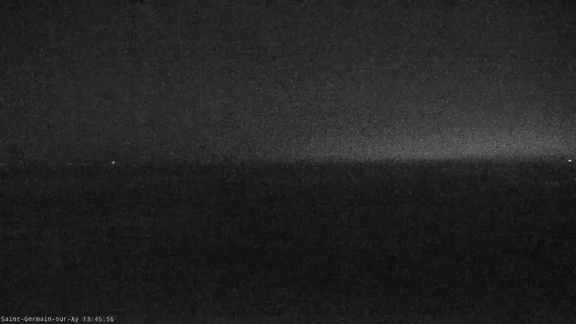 A low-light, grainy image shows a dark horizon line with a slightly brighter band of light near the top.