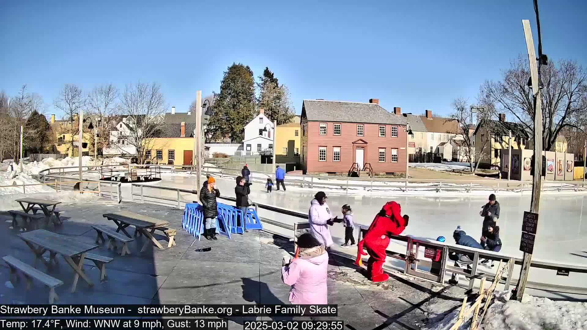 People ice skate on an outdoor rink on a sunny day with a temperature of 17.4°F and a west-northwest wind of 9 mph gusting to 13 mph.