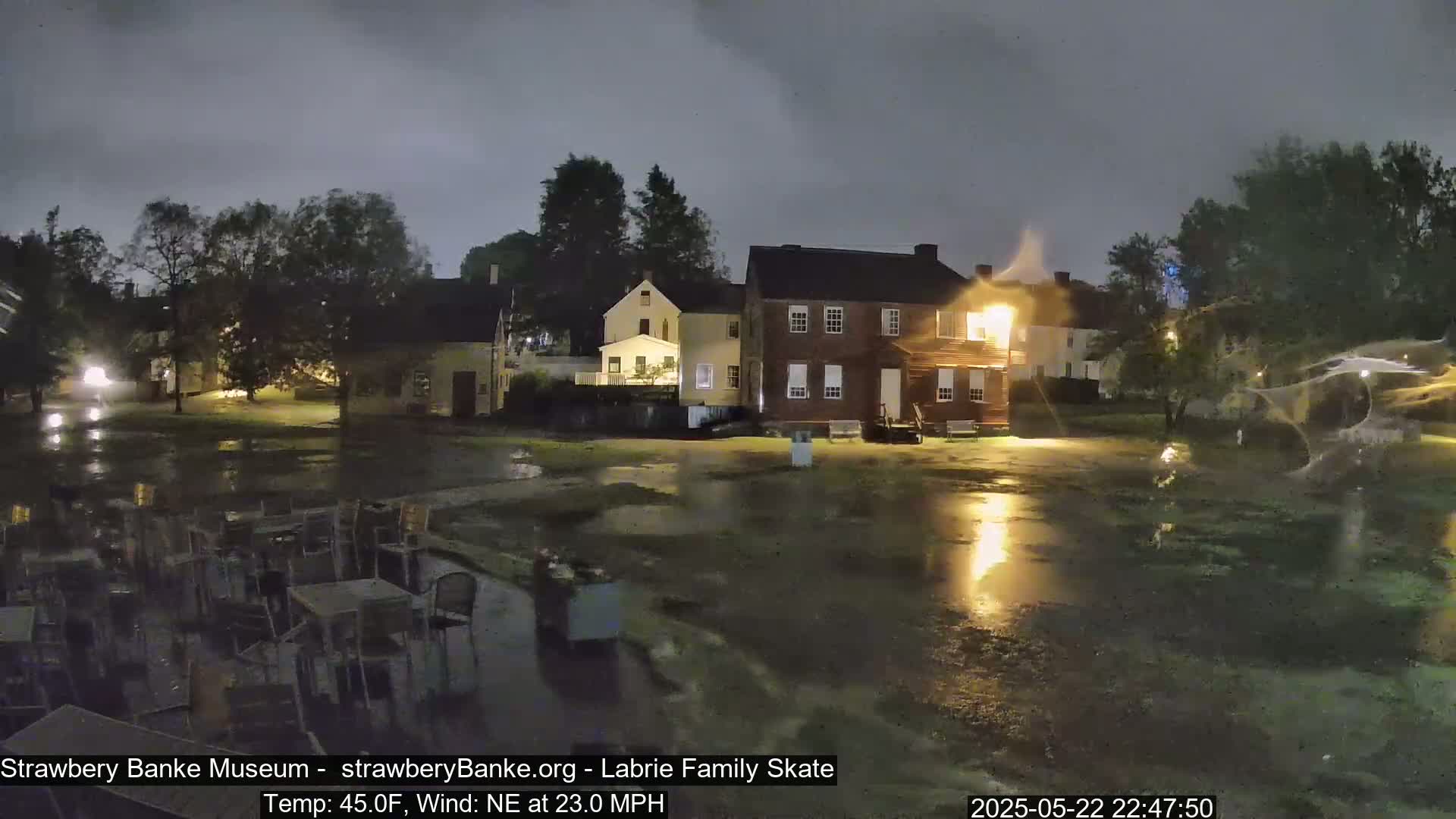 A nighttime scene of several buildings with a flooded, outdoor area, under a dark, stormy sky.