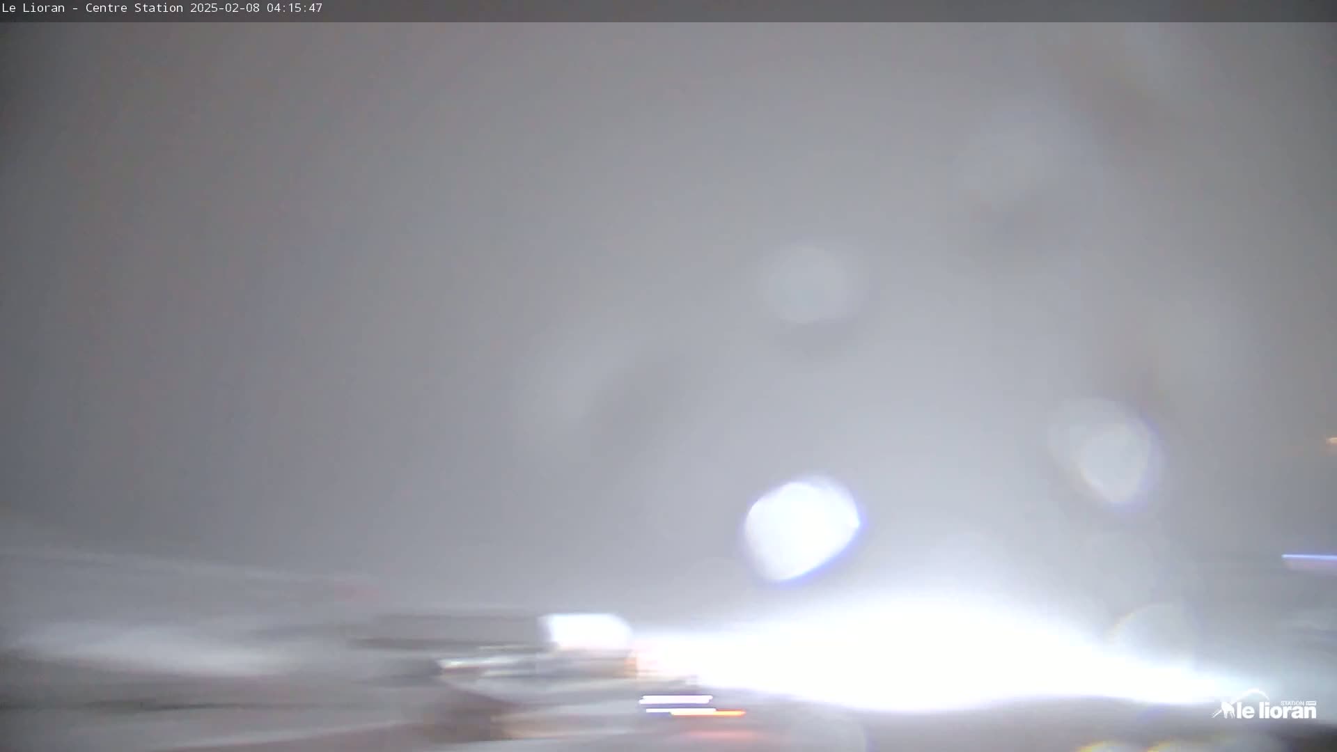A blurry, hazy scene of what appears to be a roadway in heavy fog or snow.