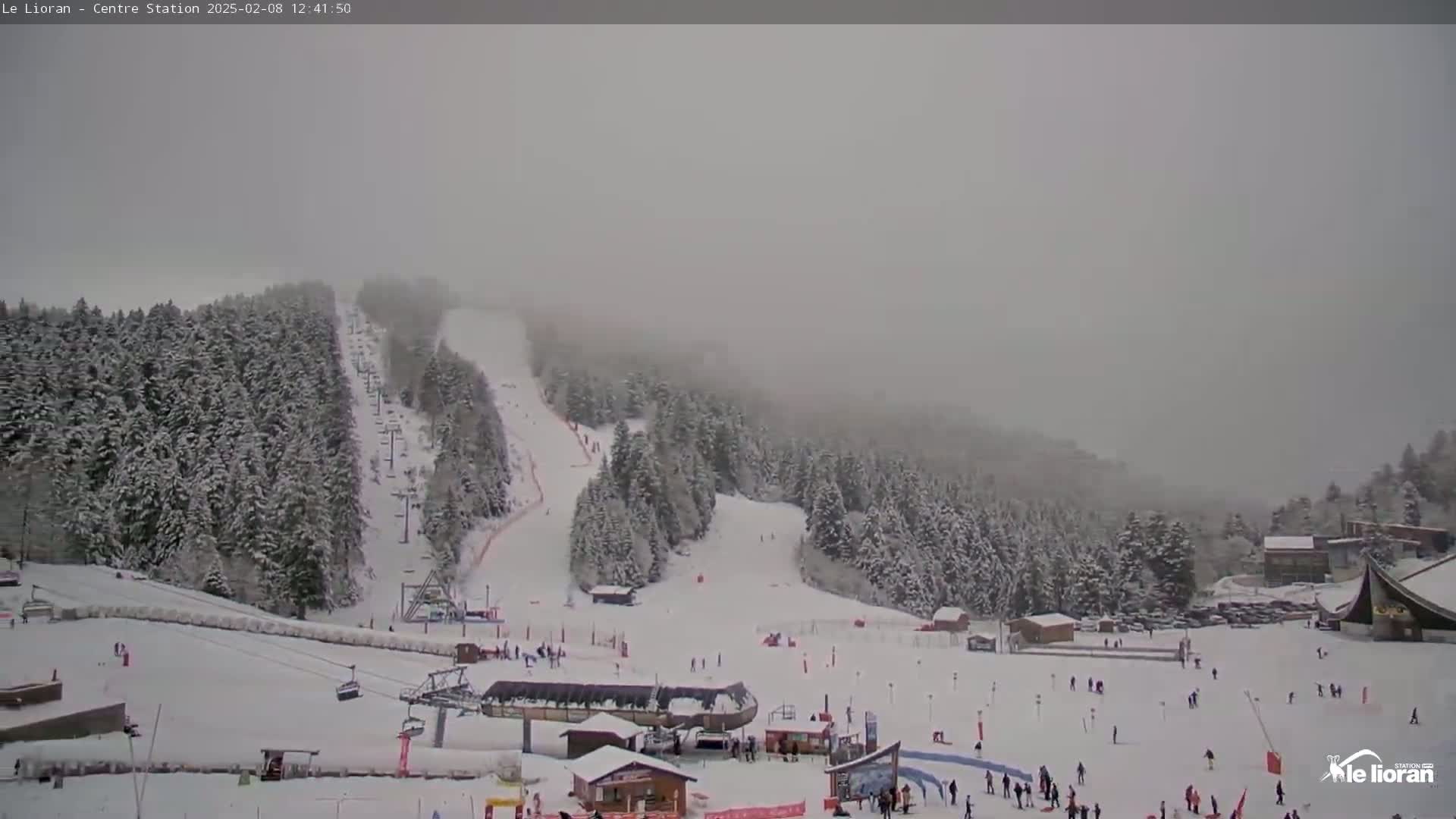 A snow-covered ski resort with skiers and chairlifts is visible in hazy snowy conditions.