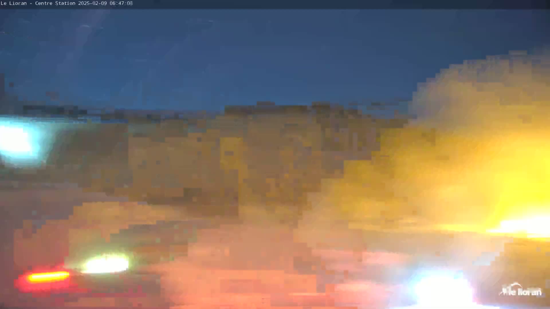 Blurry nighttime footage shows headlights of vehicles moving through a hazy, yellow-orange atmosphere.