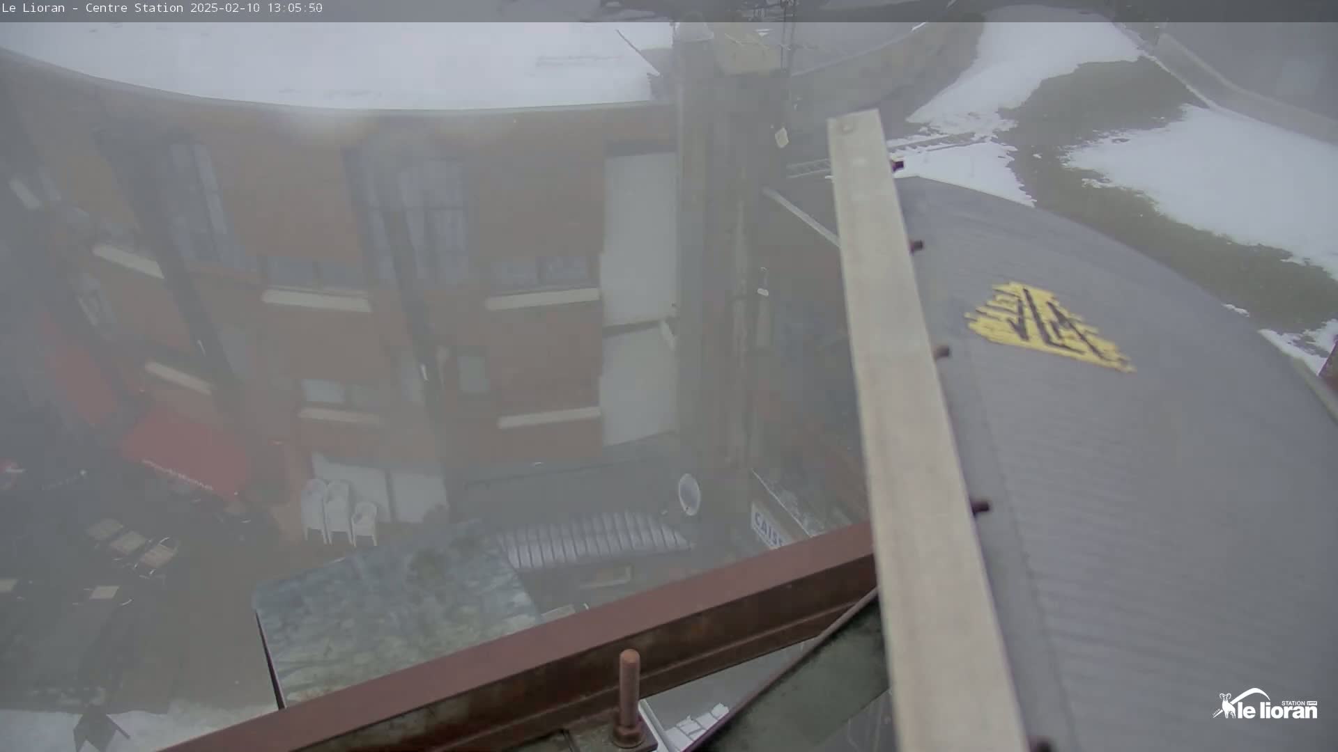 A hazy, foggy view from above shows a multi-story building with outdoor seating, partially obscured by a metal structure.
