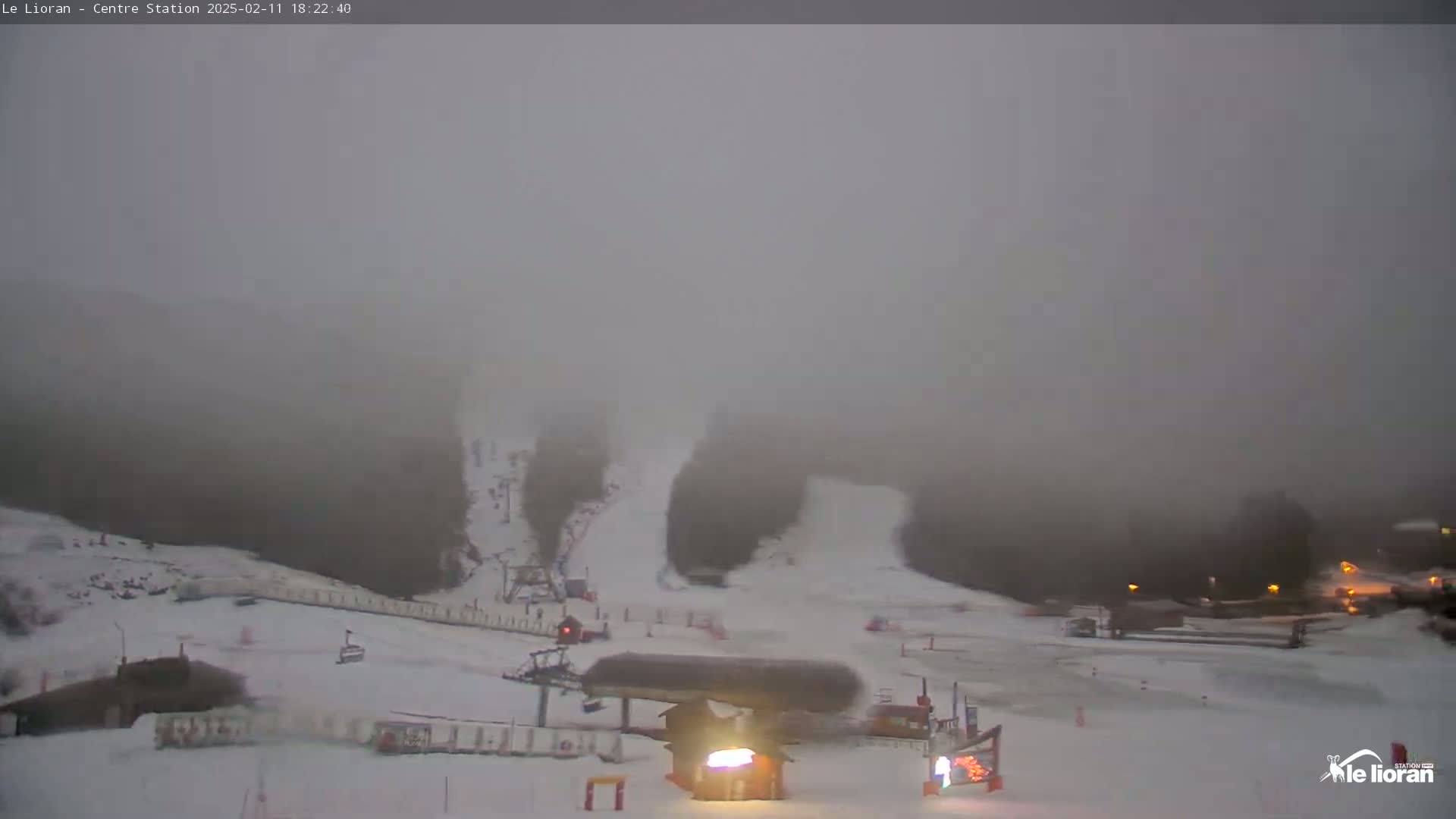 A foggy, snowy ski resort scene at night shows a ski lift and snow-covered slopes.