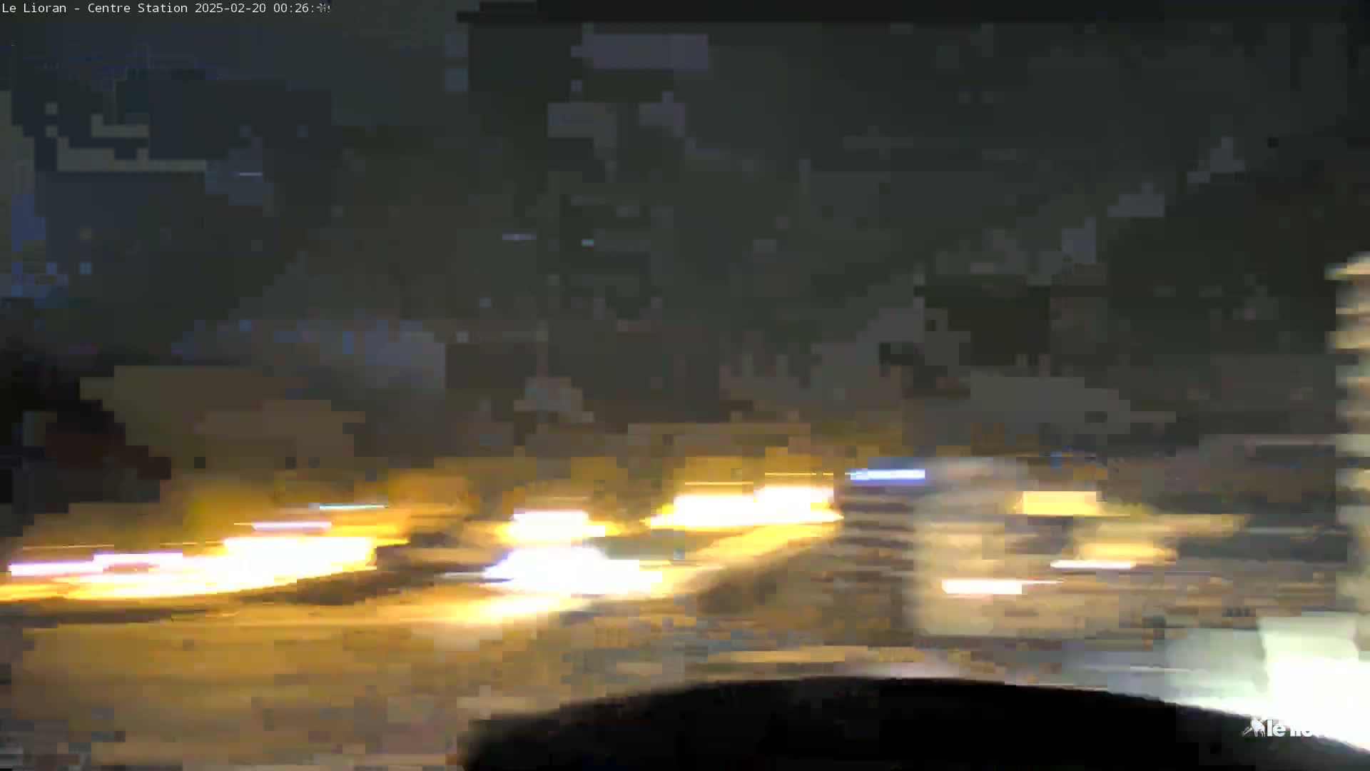 A nighttime view of blurred headlights from multiple vehicles traveling on a road.