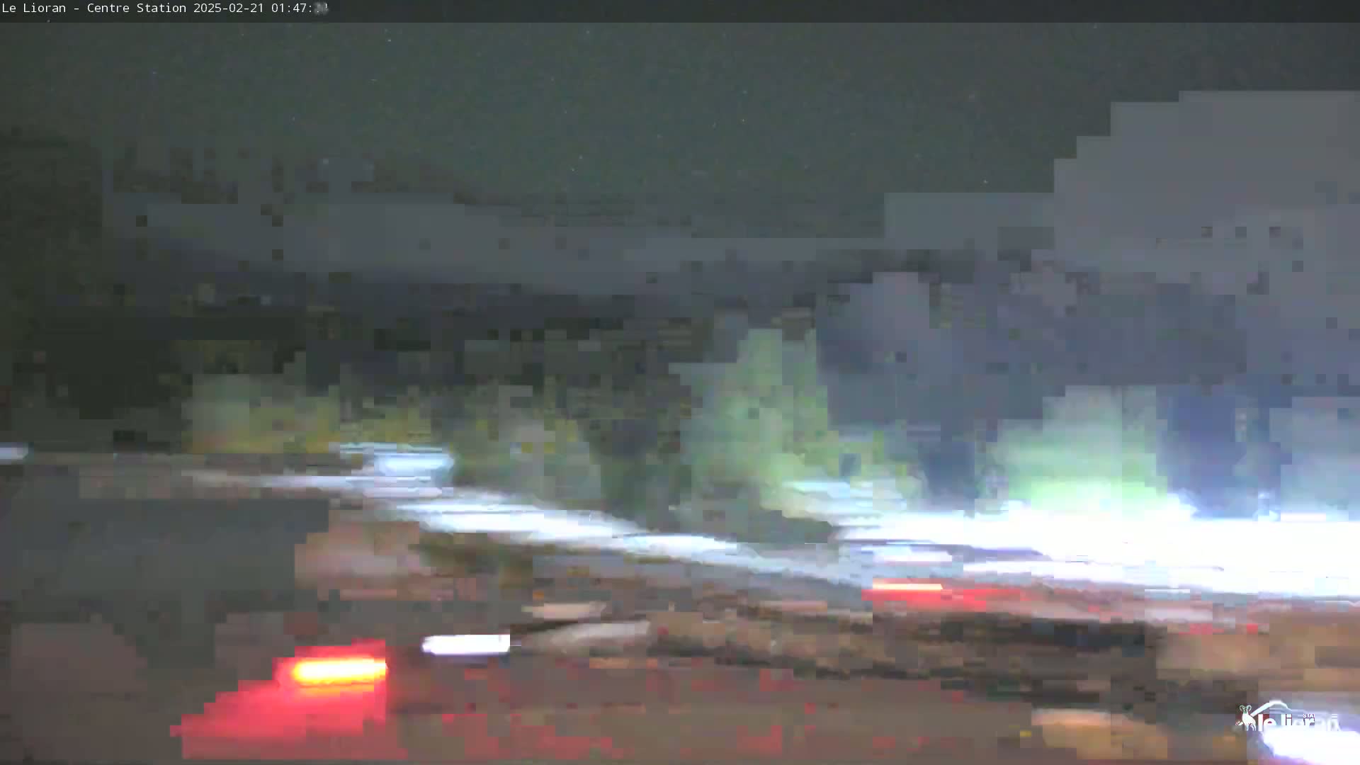 A nighttime, blurry view of a road with vehicles' taillights visible, under a slightly overcast sky.