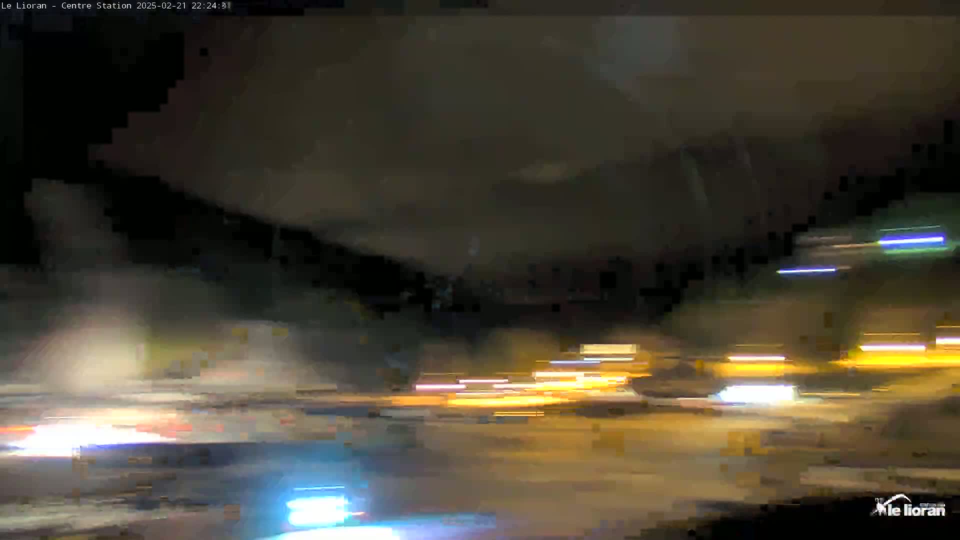 A nighttime view of blurred lights from vehicles on a road, possibly under an overpass.
