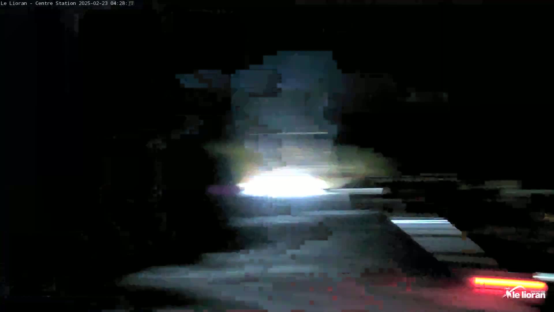 A bright light obscures the view of a dark, nighttime scene, possibly a road with blurred vehicle lights.