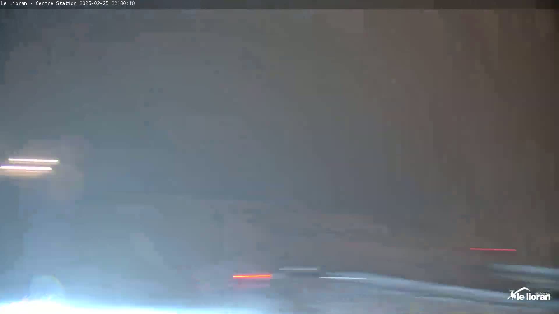 A hazy, low-light outdoor scene shows blurred streaks of light suggesting vehicles moving on a road.