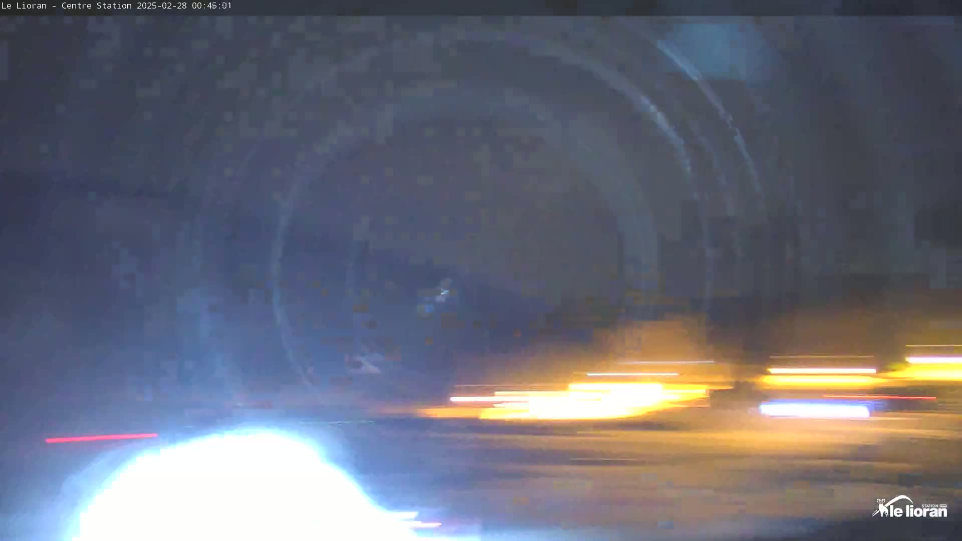 Blurry nighttime images of light trails from vehicles appear to be moving on a road.