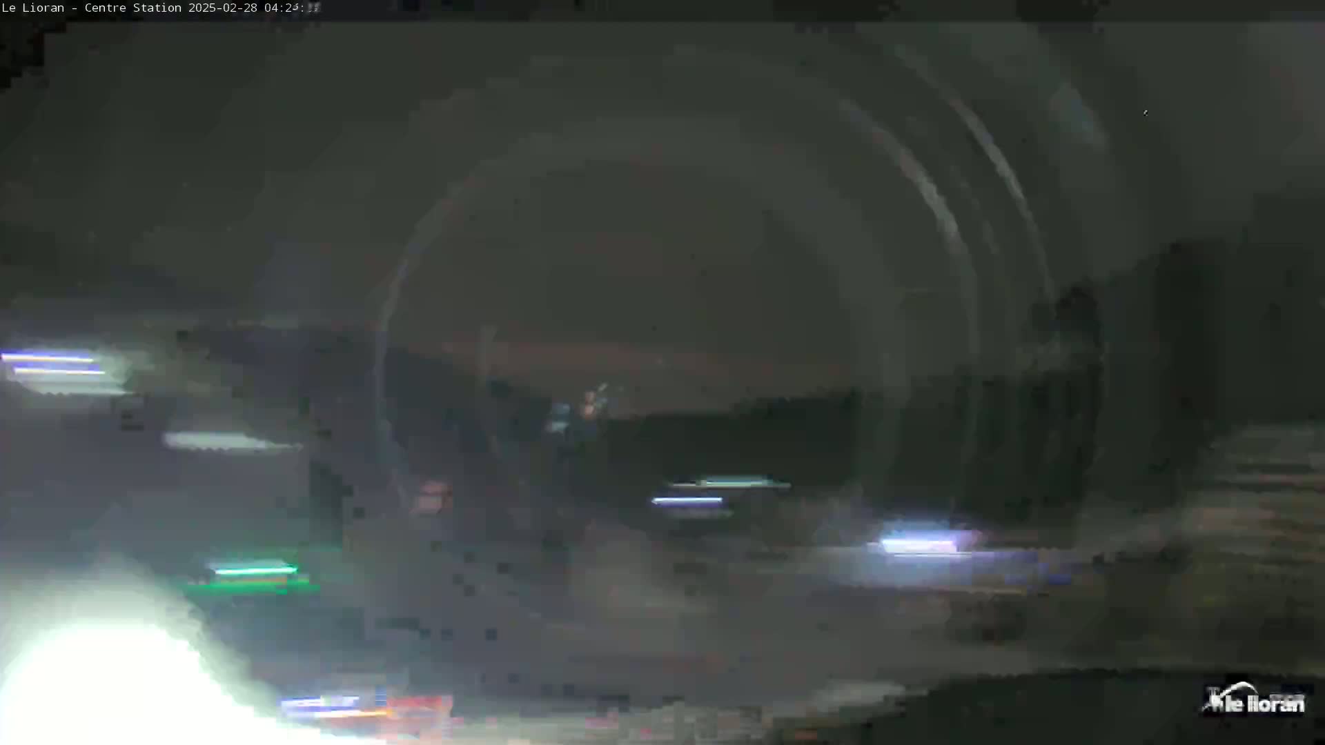 A nighttime, blurry view of a roadway with vehicle lights visible in the distance and possibly some light rain or fog.